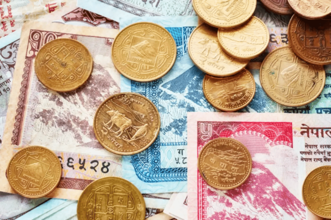A close-up of Nepalese rupee coins and banknotes laid out together.
