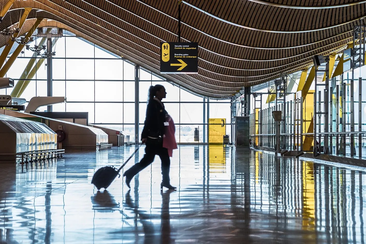 Traveller walking with luggage through a modern airport terminal.