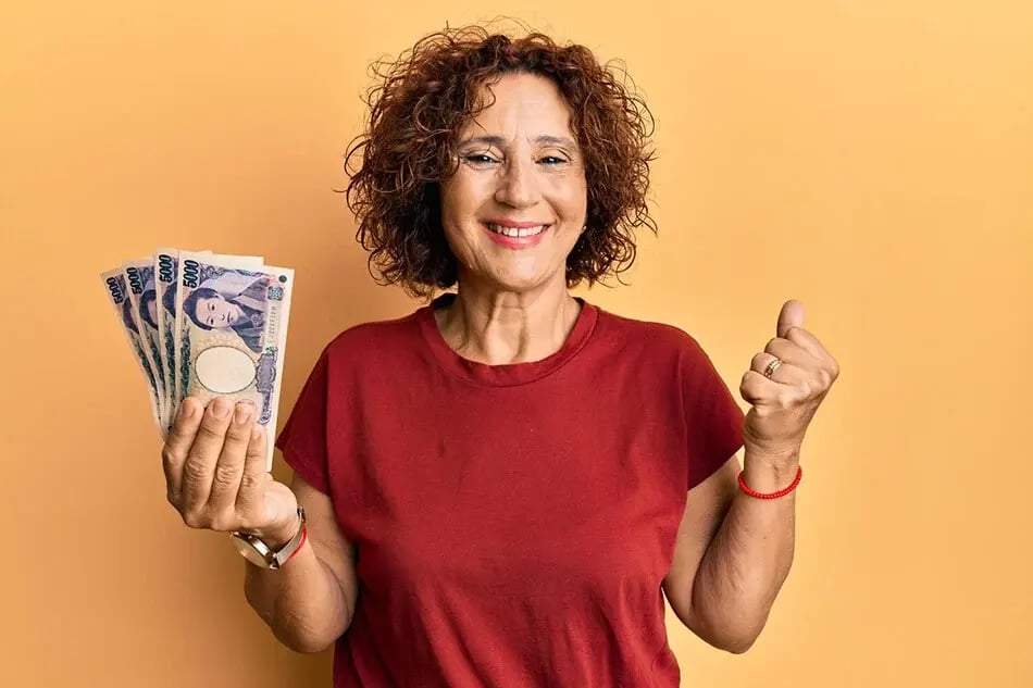 Woman celebrating while holding Japanese yen cash