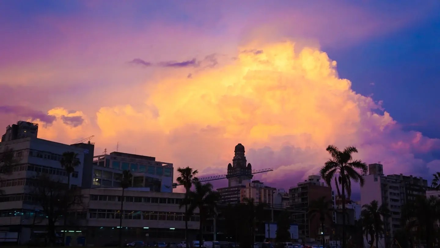 Dramatic sunset sky over a Colombian coastal city with silhouetted palm trees