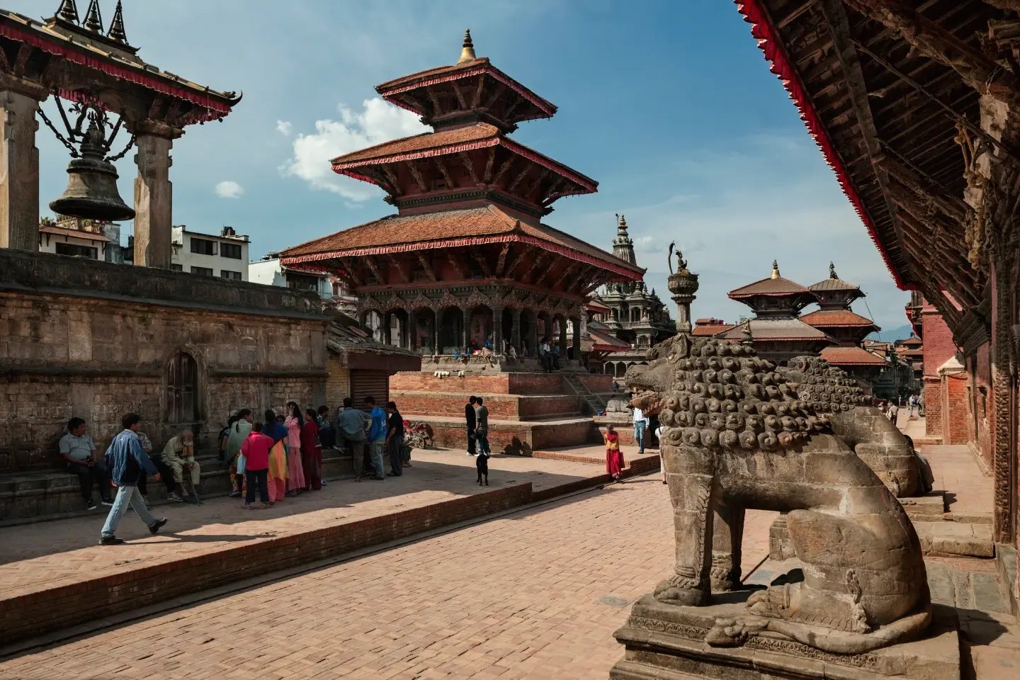 Pagoda-style temples and a stone lion statue in Kathmandu Durbar Square, Nepal.