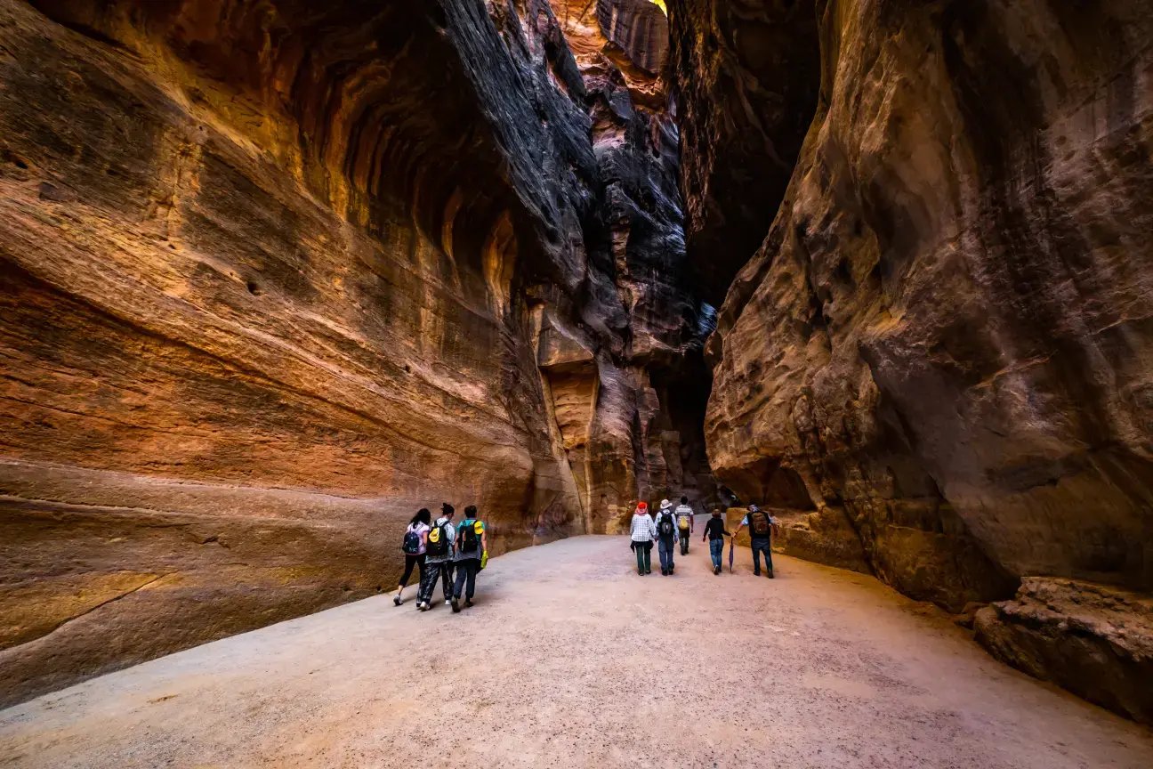 Visitors walking through the narrow sandstone Siq canyon leading into Petra