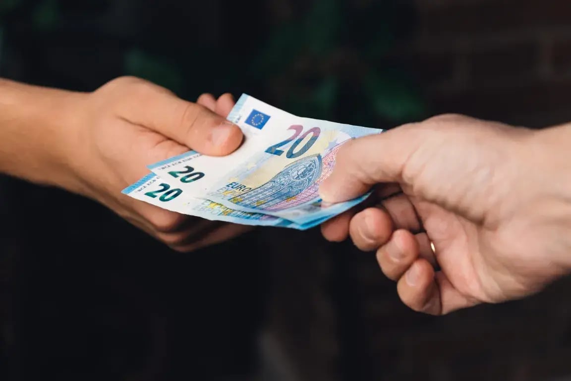 Close-up of hands exchanging euro banknotes