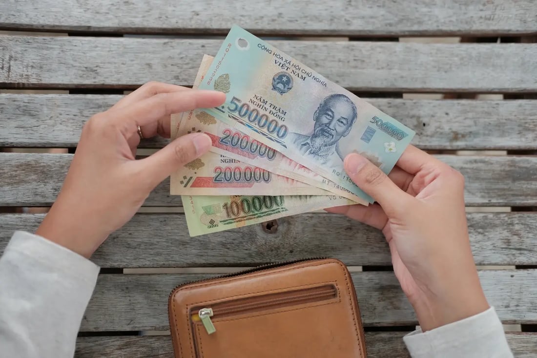Hands holding Vietnamese dong banknotes over wooden table