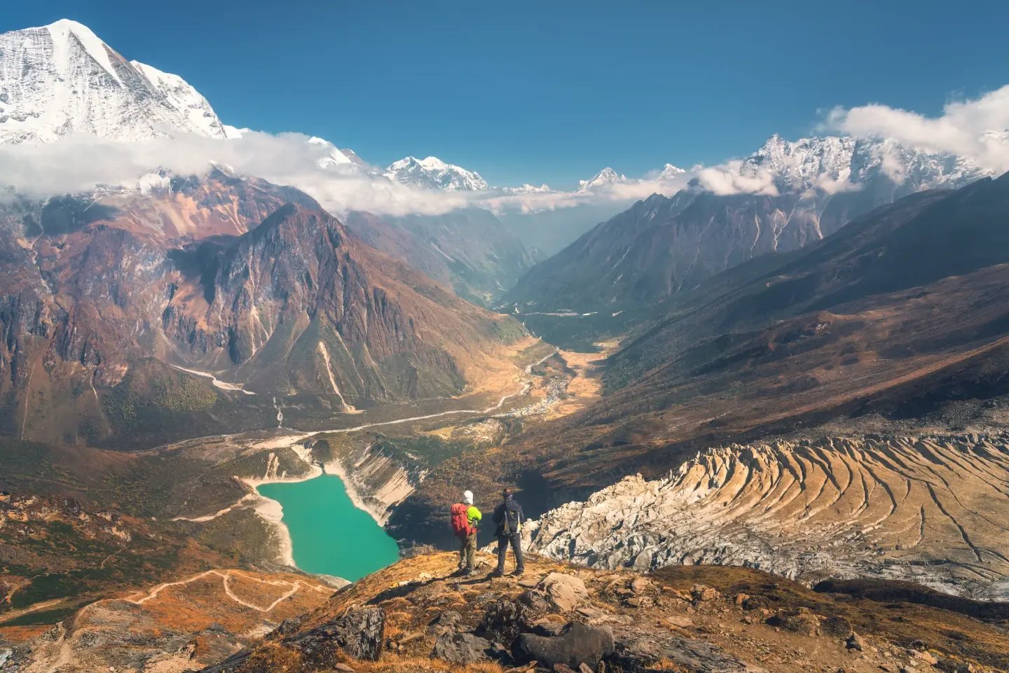 Trekkers walking beside a turquoise high-altitude lake in the Everest region.