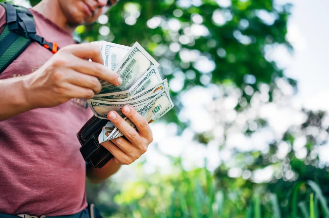 Traveller counting US dollar notes while preparing foreign currency for overseas travel and money exchange.