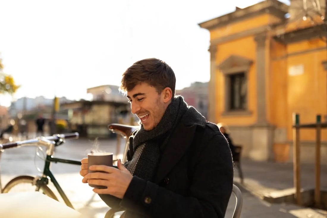 Traveller enjoying a hot coffee at a Paris café, using euros for a relaxed local experience.
