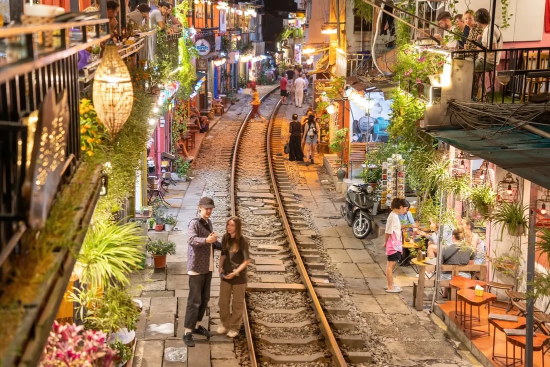 Narrow train street in Hanoi with cafes and people along the railway tracks