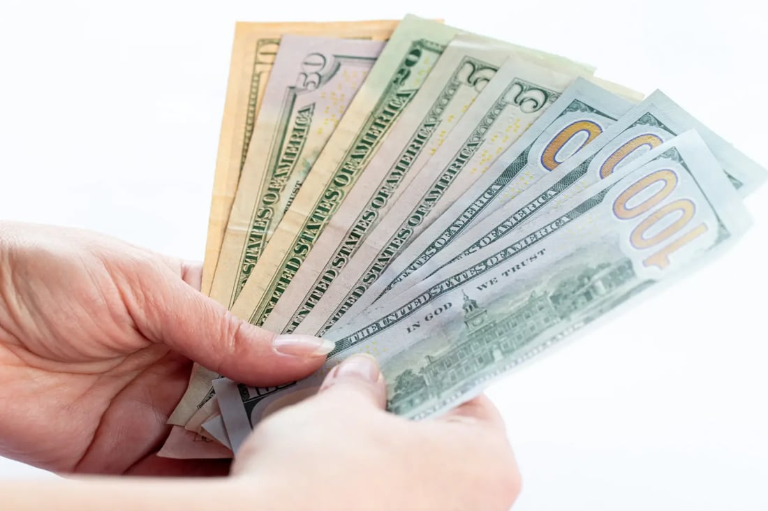 Close-up of hand holding US dollar banknotes including $100 bills