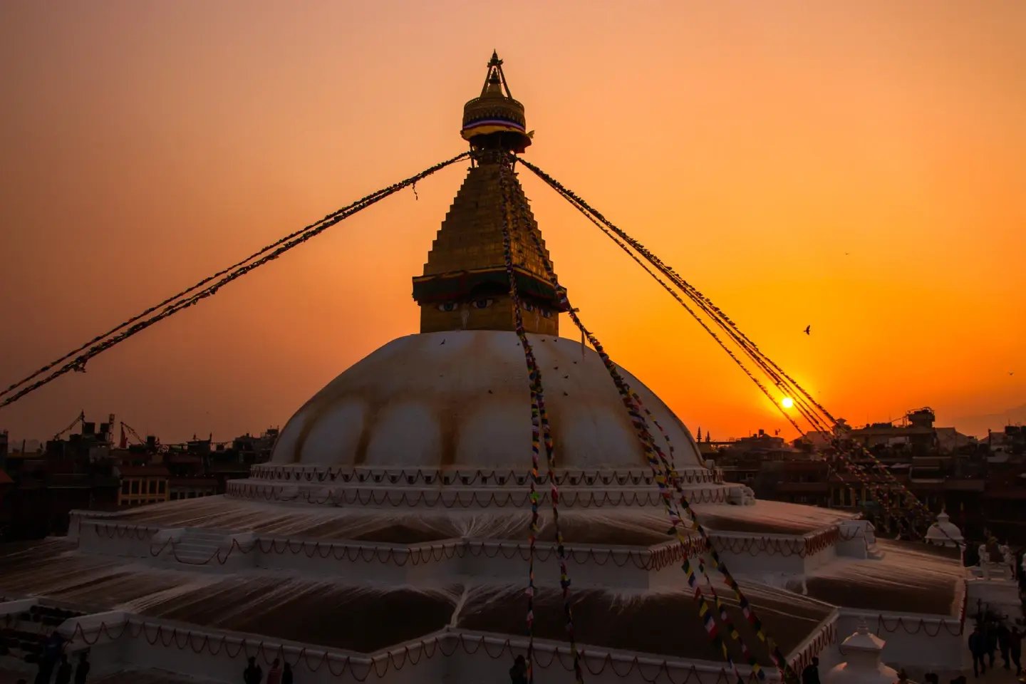 Boudhanath Stupa silhouetted against an orange sunset sky, Kathmandu, Nepal
