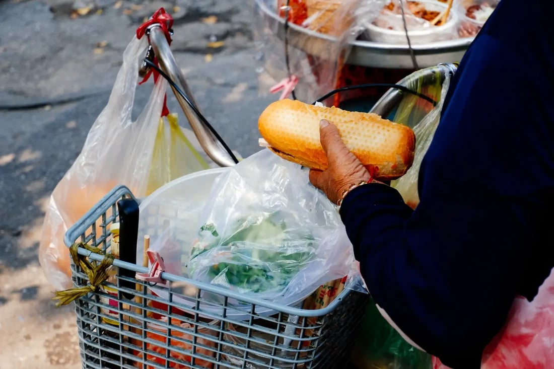 Street food vendor handing over a Vietnamese banh mi into a basket