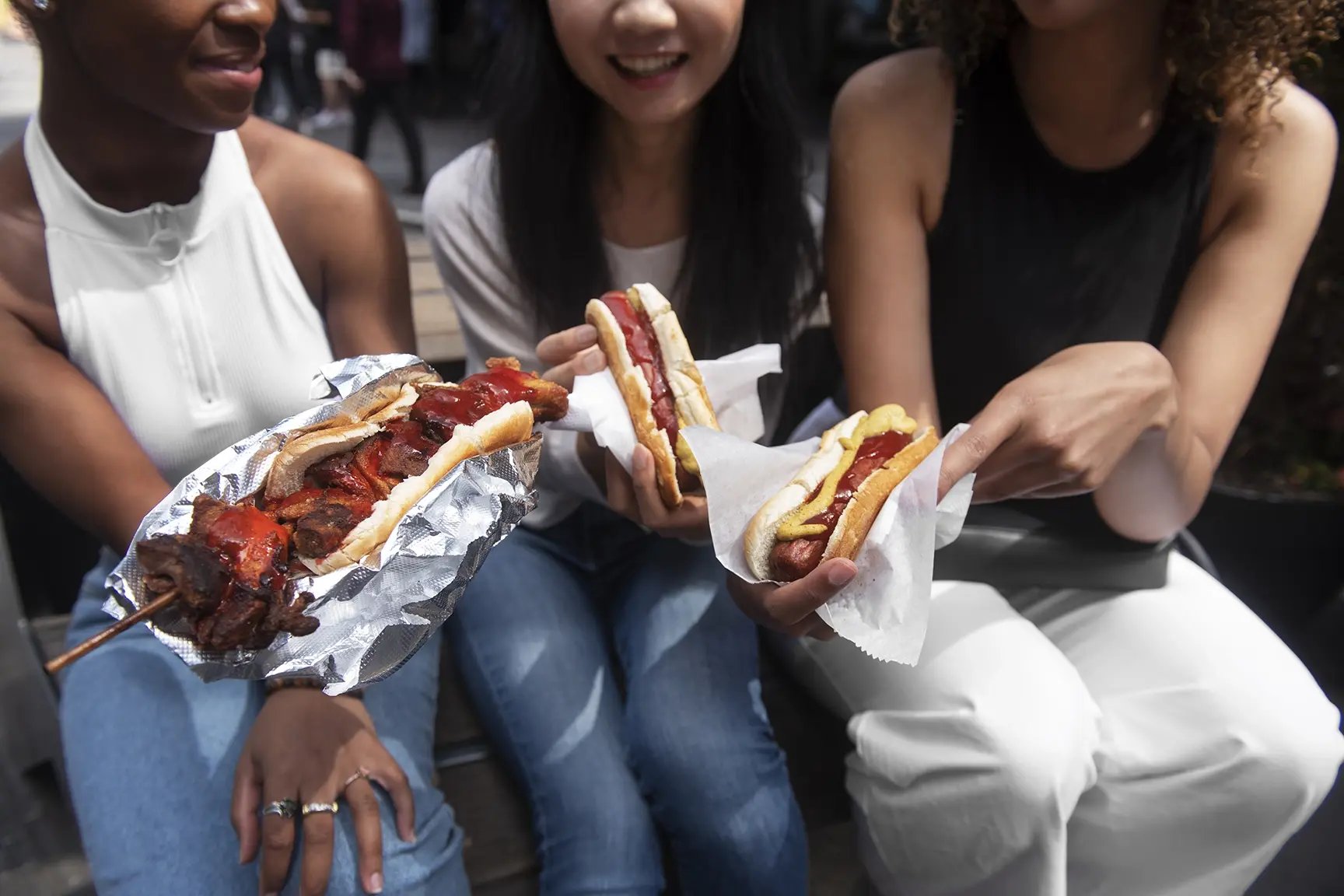 Friends eating hotdogs and street food in New York City.