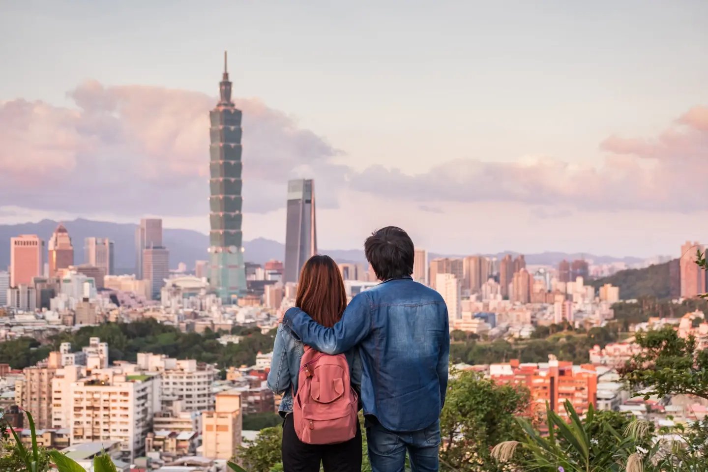 Couple admiring the Taipei skyline and Taipei 101 from a hillside at sunset