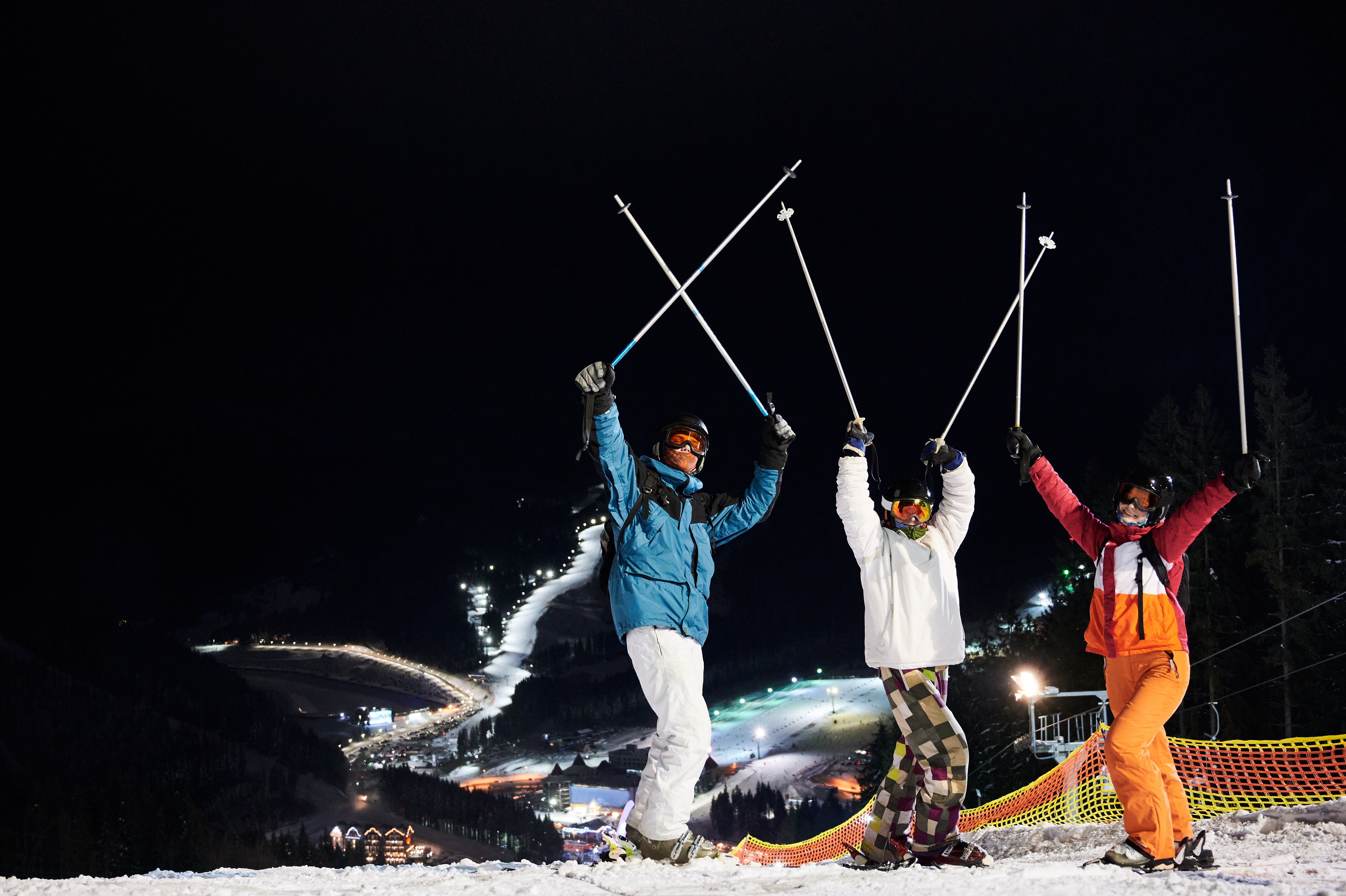 Skiers celebrating at night in an alpine resort during winter in Italy