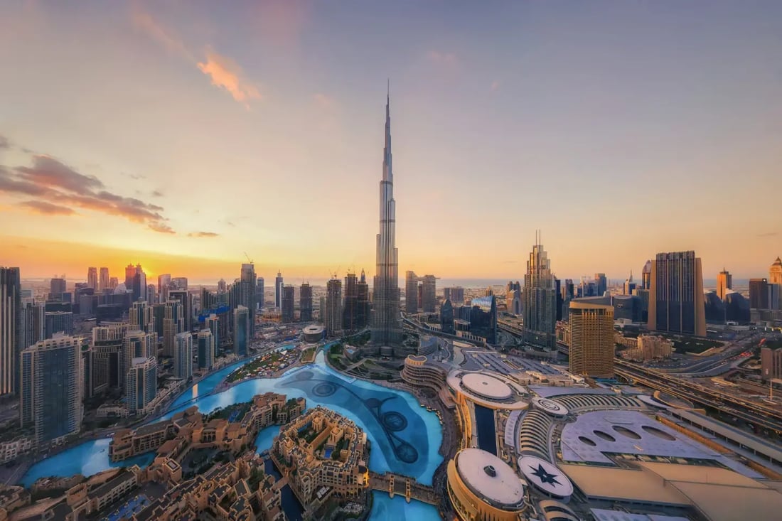 Woman in a blue scarf walking along a promenade in Downtown Dubai, with the Burj Khalifa behind