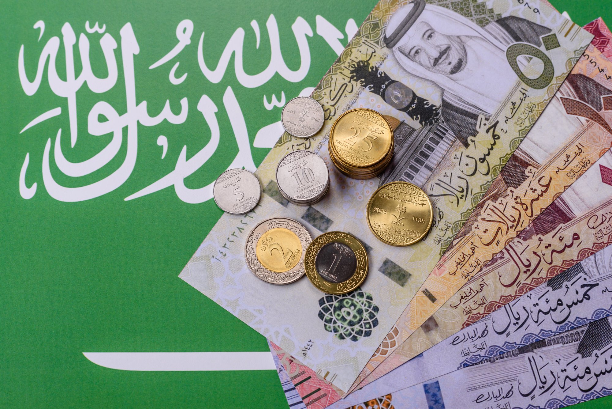 Saudi riyal coins and notes on the Saudi Arabian flag