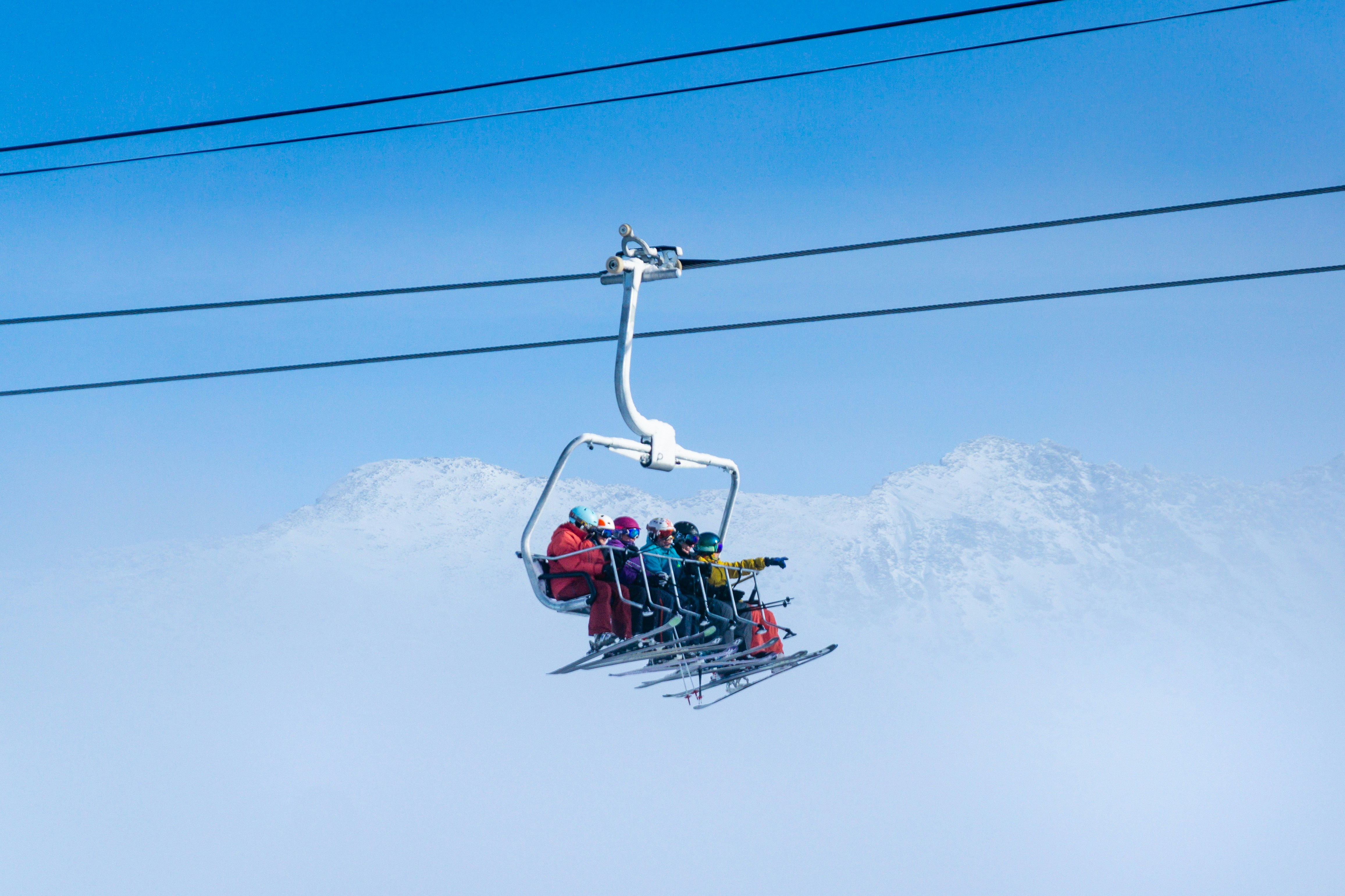 Chairlift carrying skiers above snow-covered mountains during winter